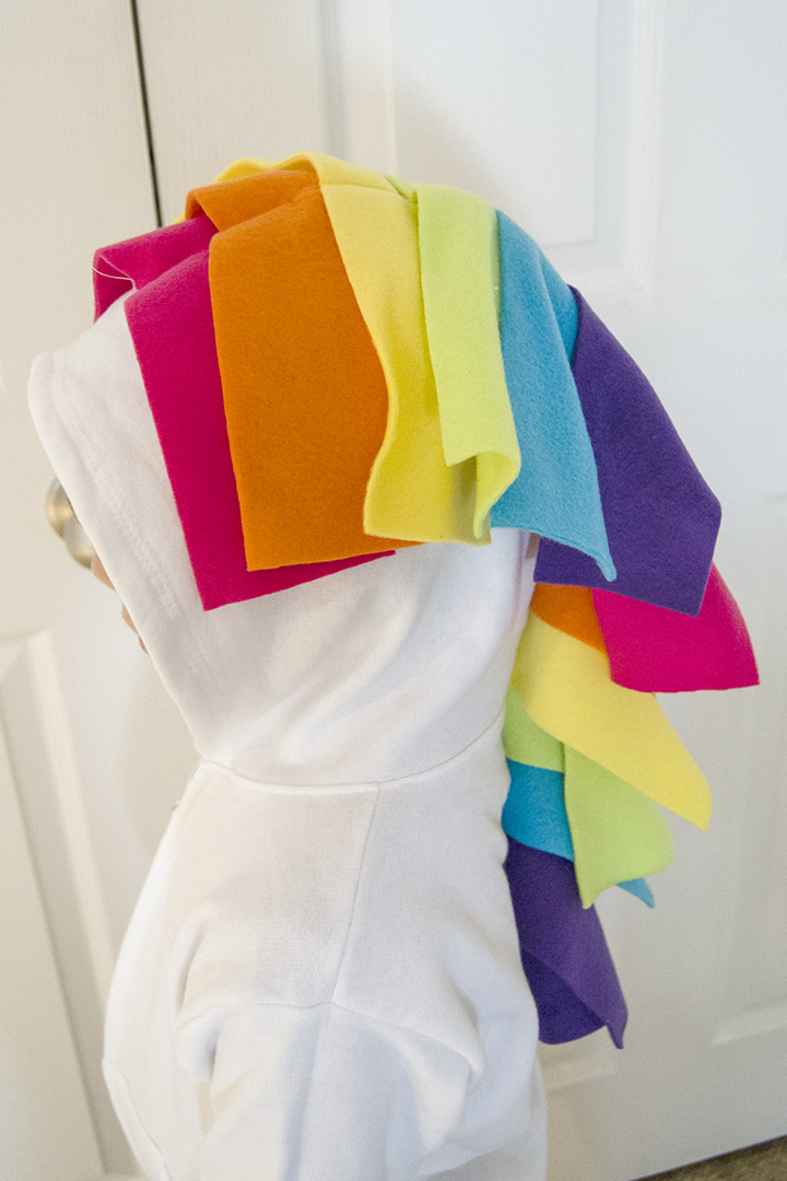 Use fleece strips to make a unicorn mane and tail on a DIY unicorn hoodie costume.