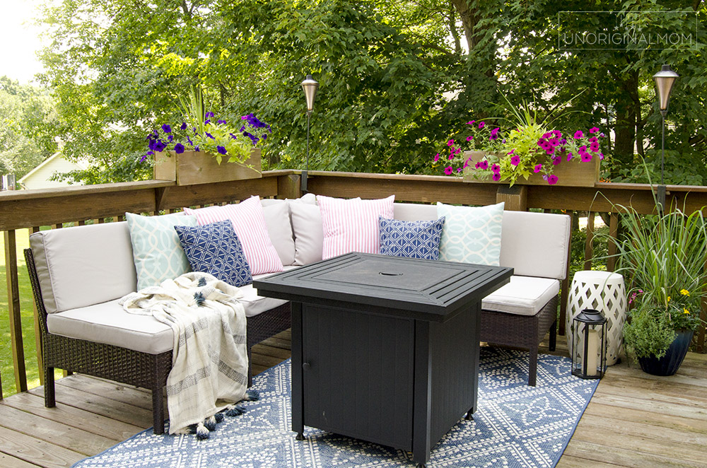 Small outdoor sectional with throw pillows and a gas fire pit on a deck | small deck decorating ideas